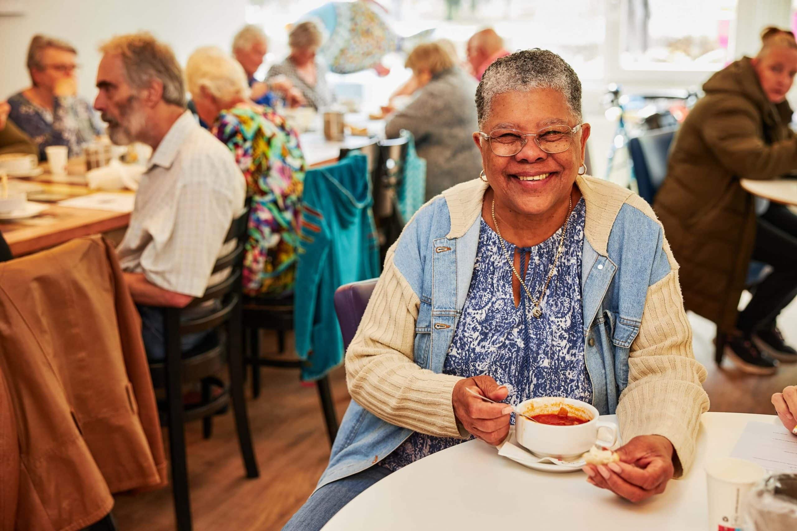 Lachende dame aan een kopje soep